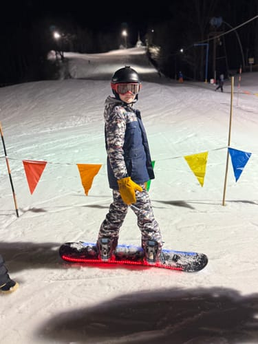 Giovane sciatore con tavola illuminata di rosso di notte sulle piste, foto inviata da un cliente